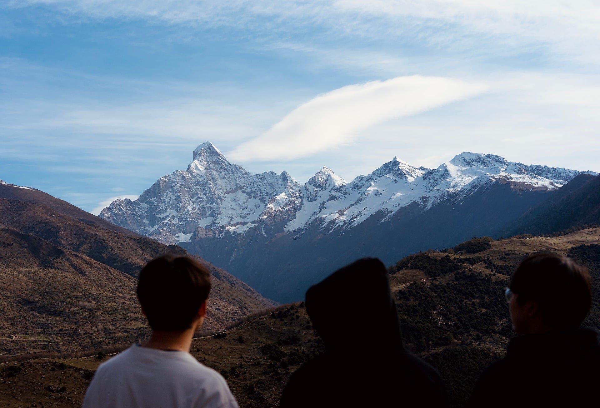 Trekkers admiring a dramatic snow-capped Himalayan peak
